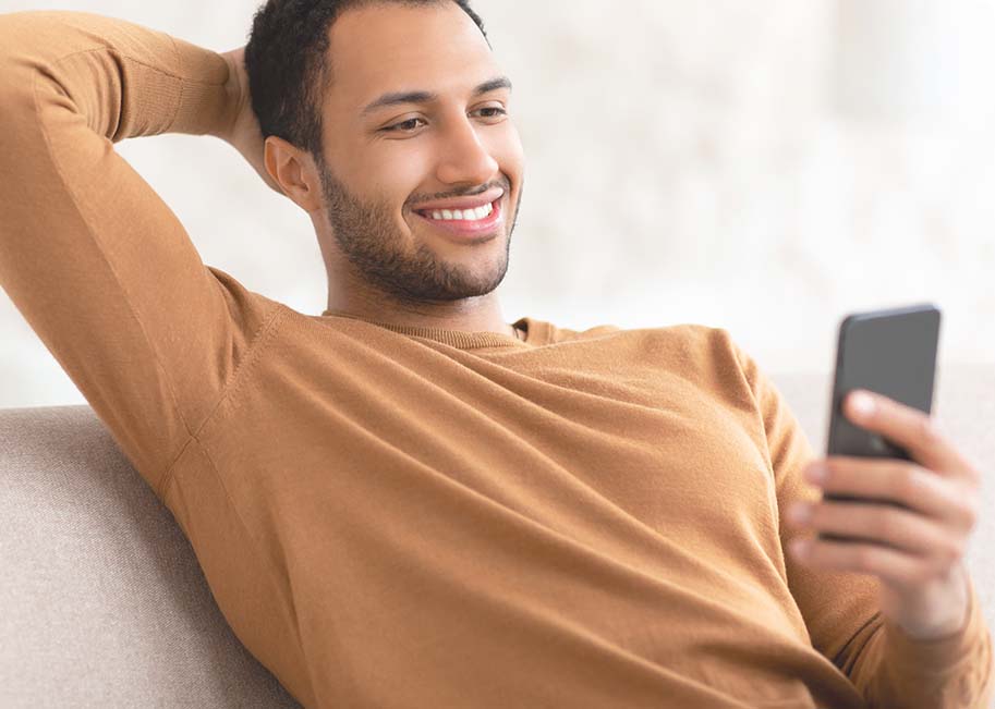 Homem sorrindo e mexendo no celular